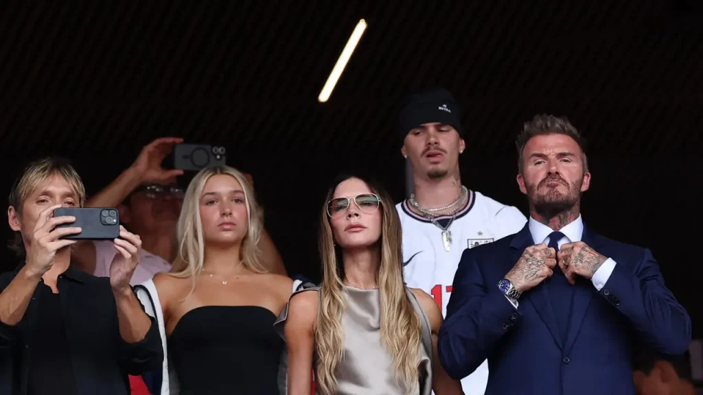 Victoria Beckham mengenakan atasan satin silver dan celana putih saat menyaksikan pertandingan Inggris vs Norwegia di Piala Dunia 2026 bersama David Beckham dan keluarga.